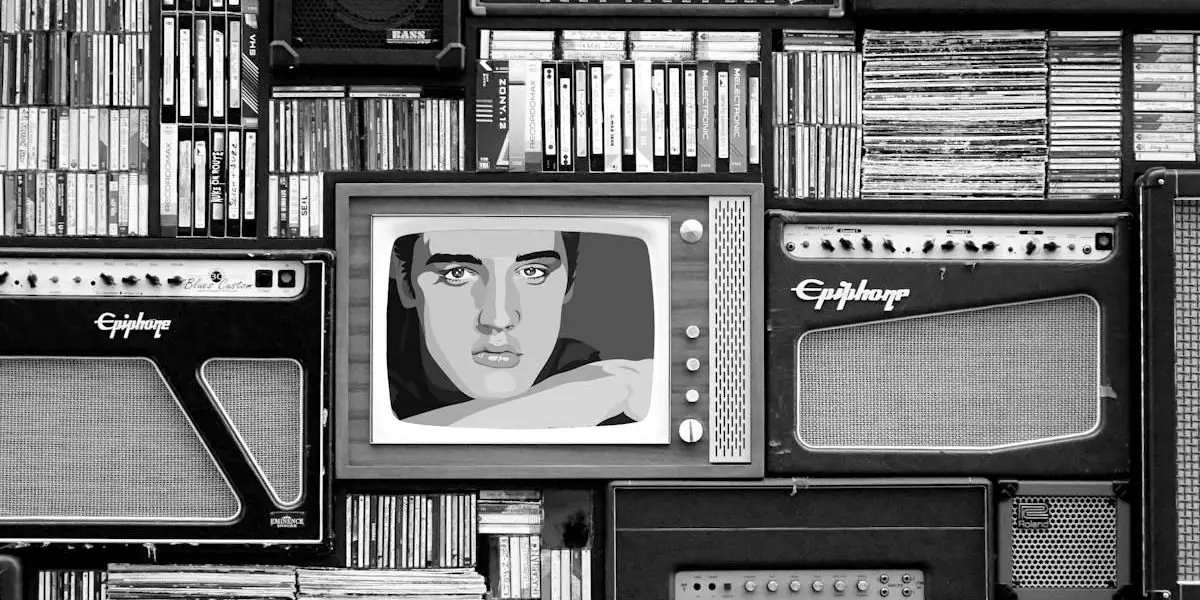 Eine Wand aus alten Fernsehern, Radios und Verstärkern in Schwarz-Weiß, auf einem Bildschirm ein gezeichnetes Porträt